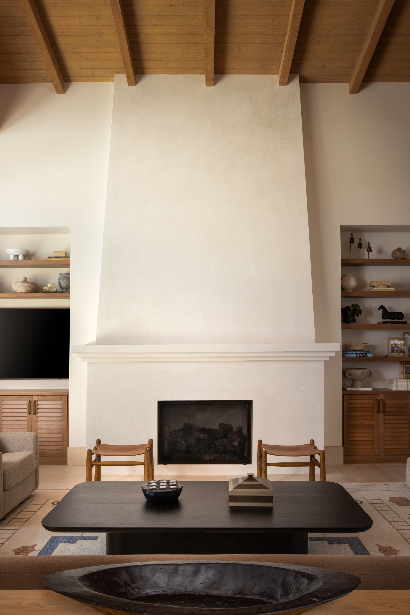 Living room with a plaster fireplace and built-in shelving under a beamed ceiling