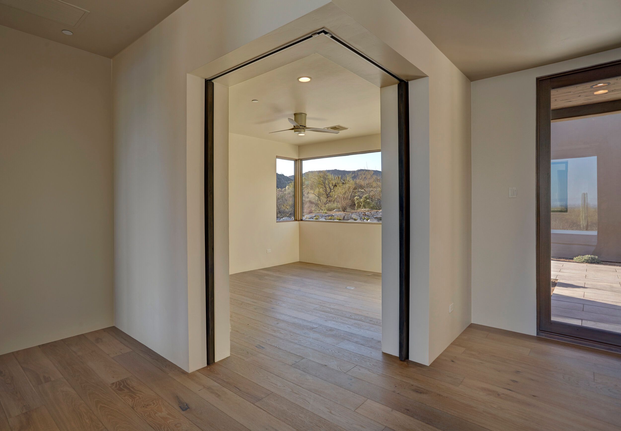 Pivot door opening between rooms with desert views beyond