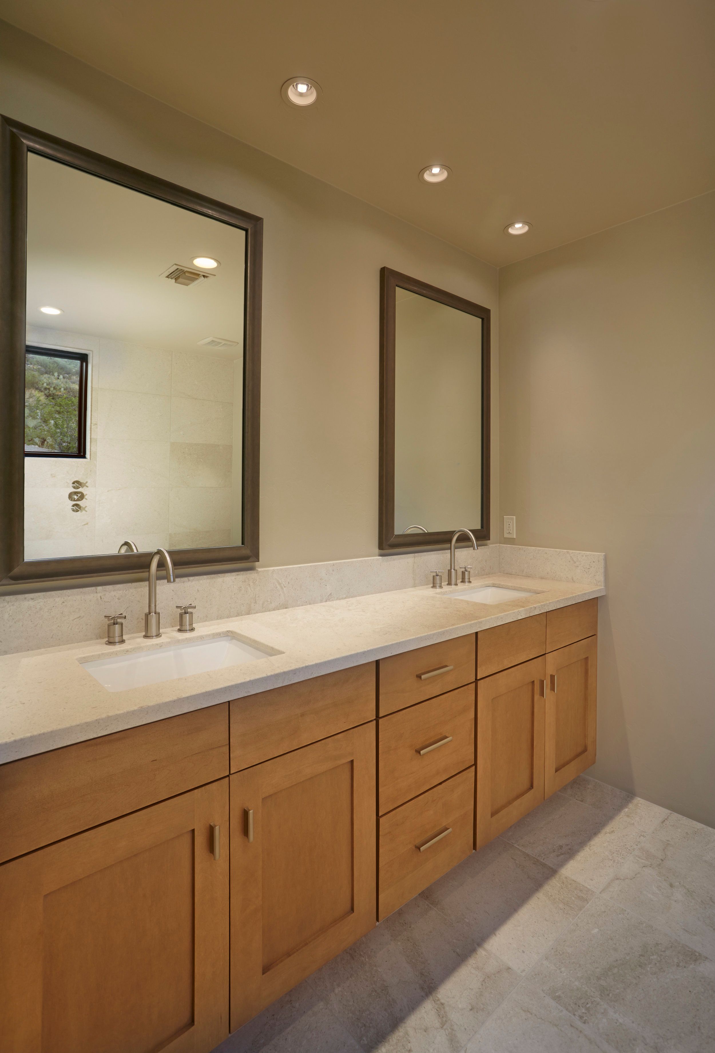 Guest bathroom with a double vanity, maple cabinetry and twin framed mirrors