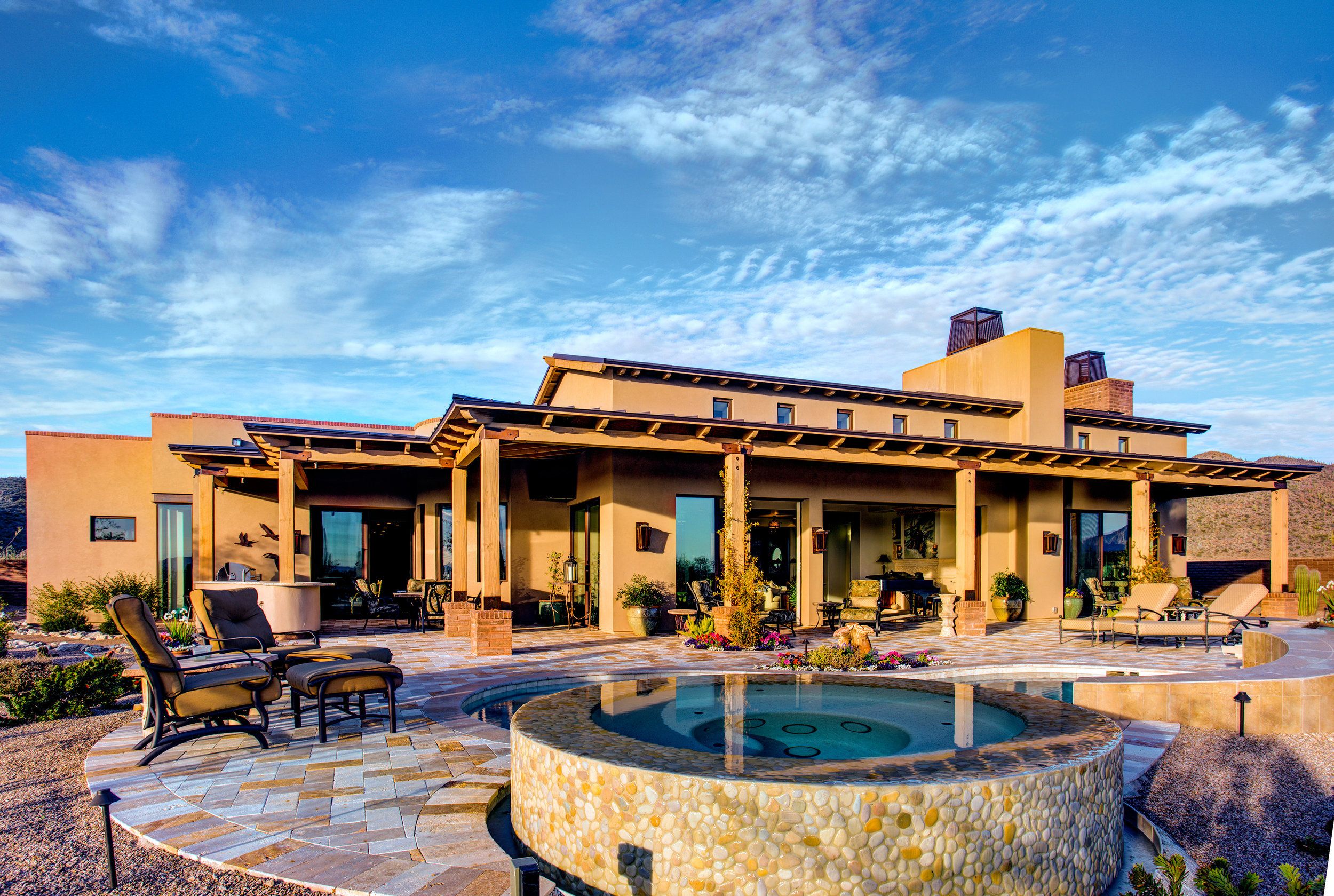 Raised stone spa and covered patio at the rear of the house under a bright desert sky
