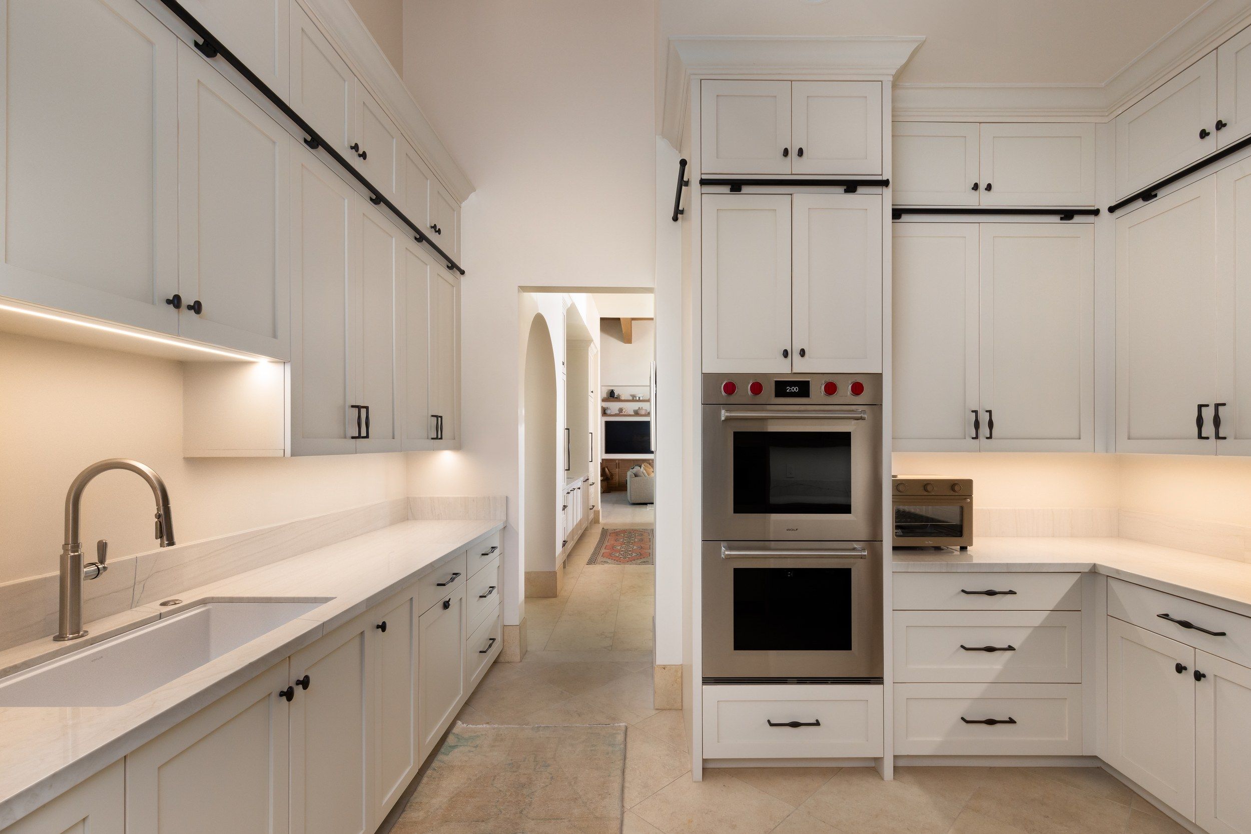 Pantry with double ovens, a farmhouse sink and an arched doorway