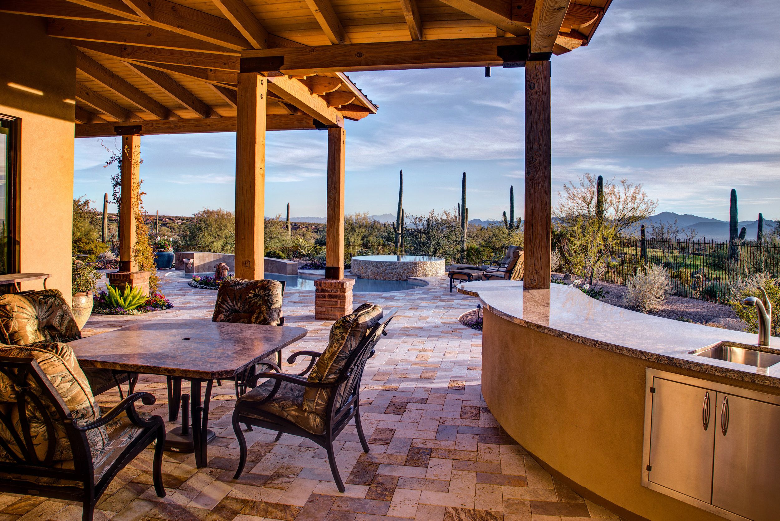 Covered outdoor dining area with a built-in bar and sink under a beamed ramada