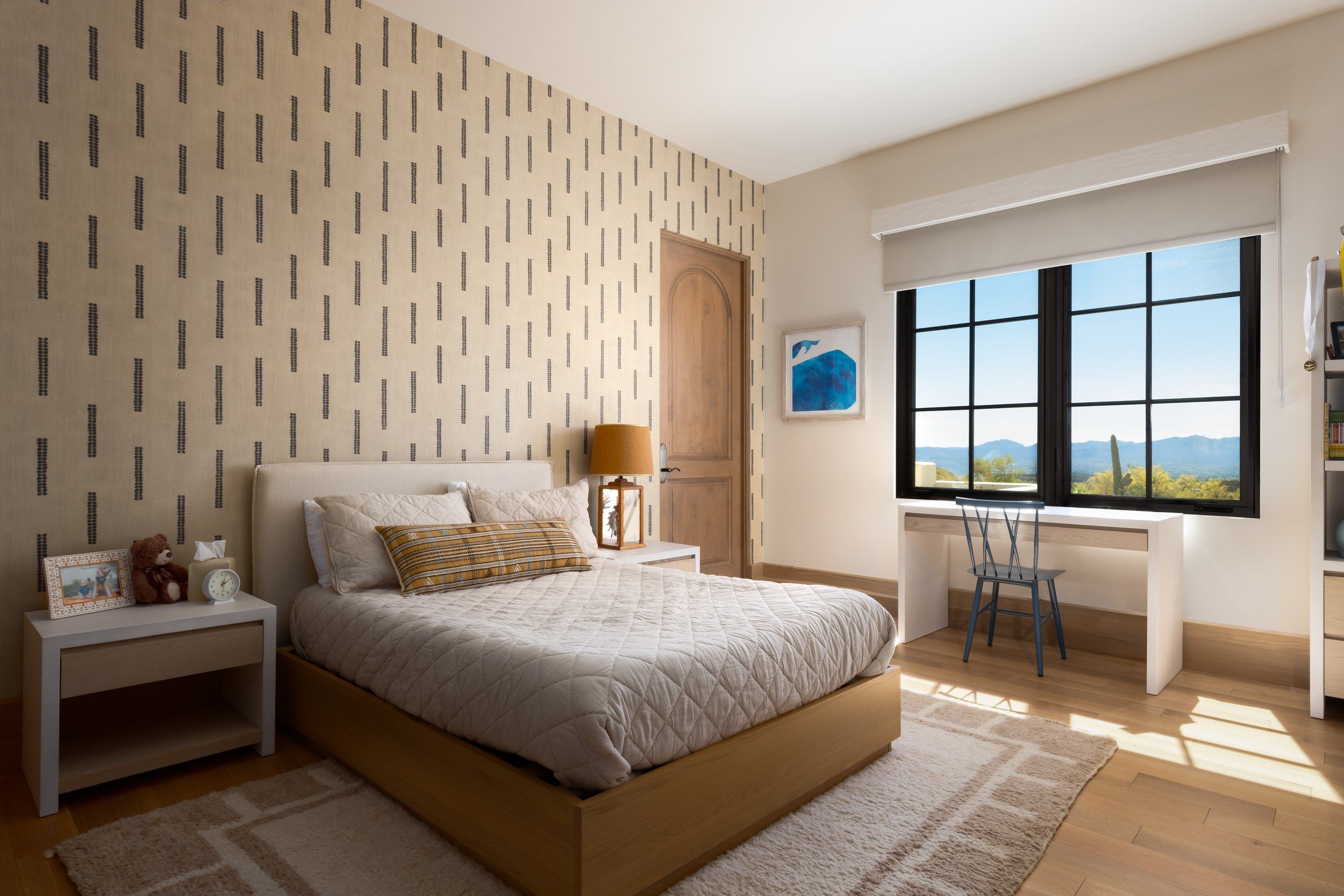 Guest bedroom with a patterned feature wall, desk and mountain view