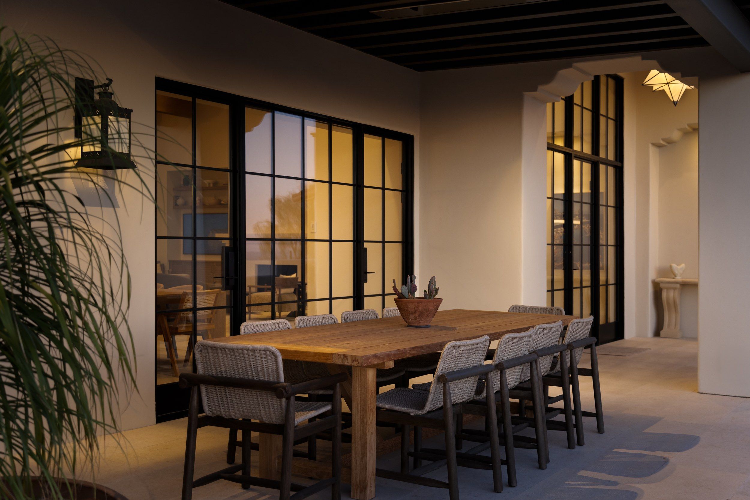 Covered patio dining at night with lantern light and steel doors